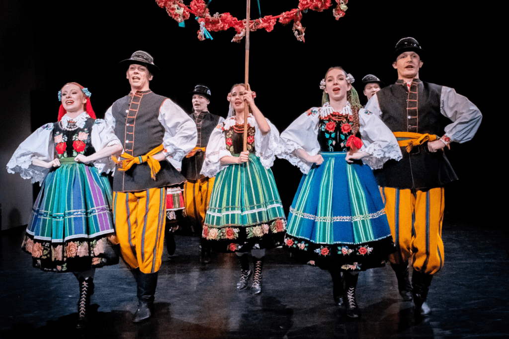 Grupa tancerzy stoi w strojach ludowych