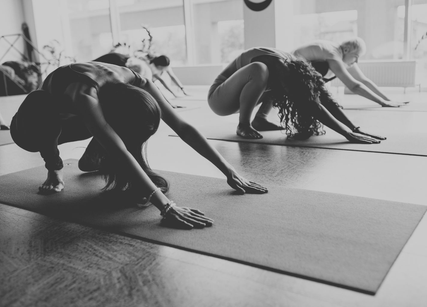 Kobiety ćwiczą joge na matach po środku sali.