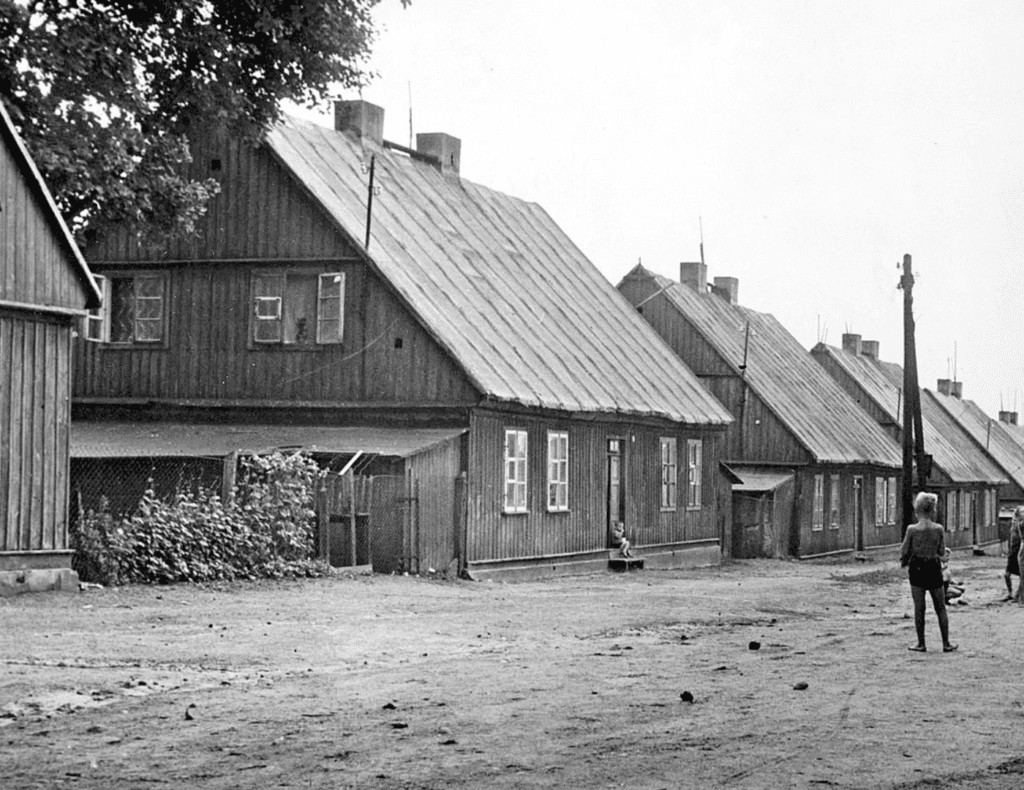 Czerno- białe zdjęcie przedstawiające szereg domków kunitzerowskich. 