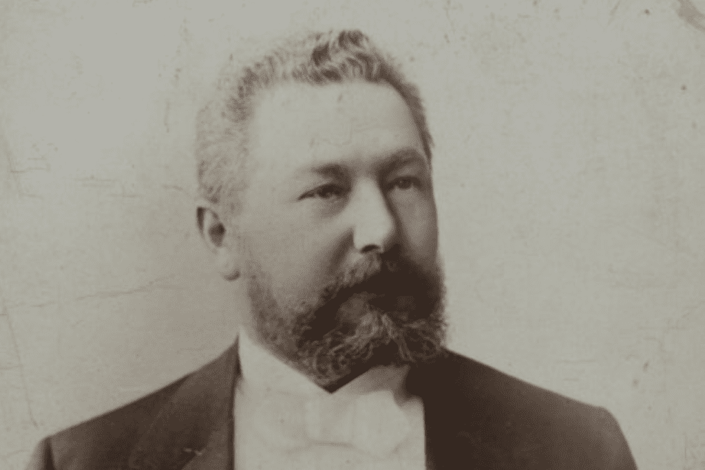 Czarno białe zdjęcie przedstawia Juliusza Kunitzera. Mężczyzna jest ubrany w elegancki strój - biała koszula i czarny smoking.