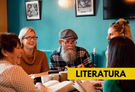 Zdjęcie przedstawia kobiety i mężczyznę w wieku dojrzałym. Osoby siedzą przy stole i czytają książki.