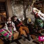 trzy osoby w kostiumach ludowych w izbie