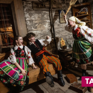 trzy osoby w kostiumach ludowych w izbie