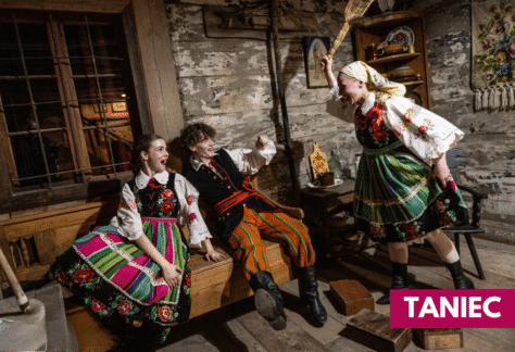 trzy osoby w kostiumach ludowych w izbie