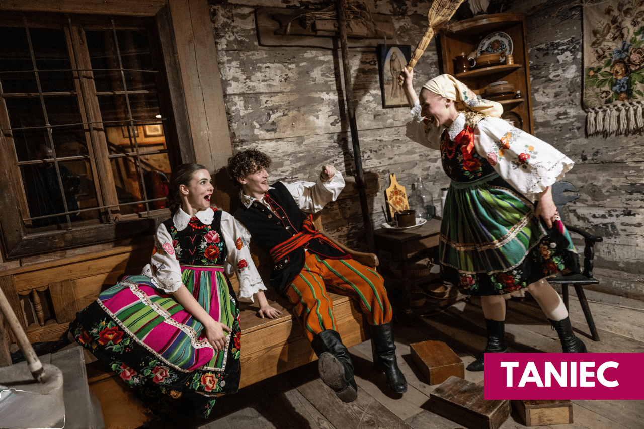 trzy osoby w kostiumach ludowych w izbie